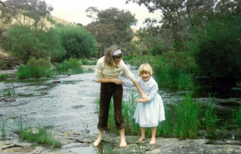 Woman and child standing on a rock in a waterfall holding hands